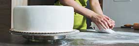 Lady icing a tiered wedding cake