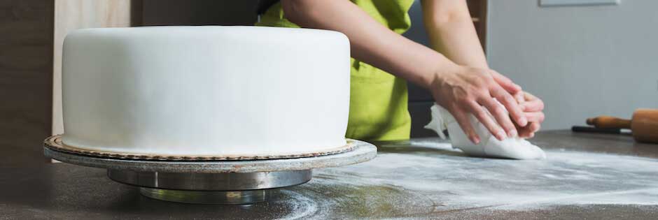 Lady icing a tiered wedding cake