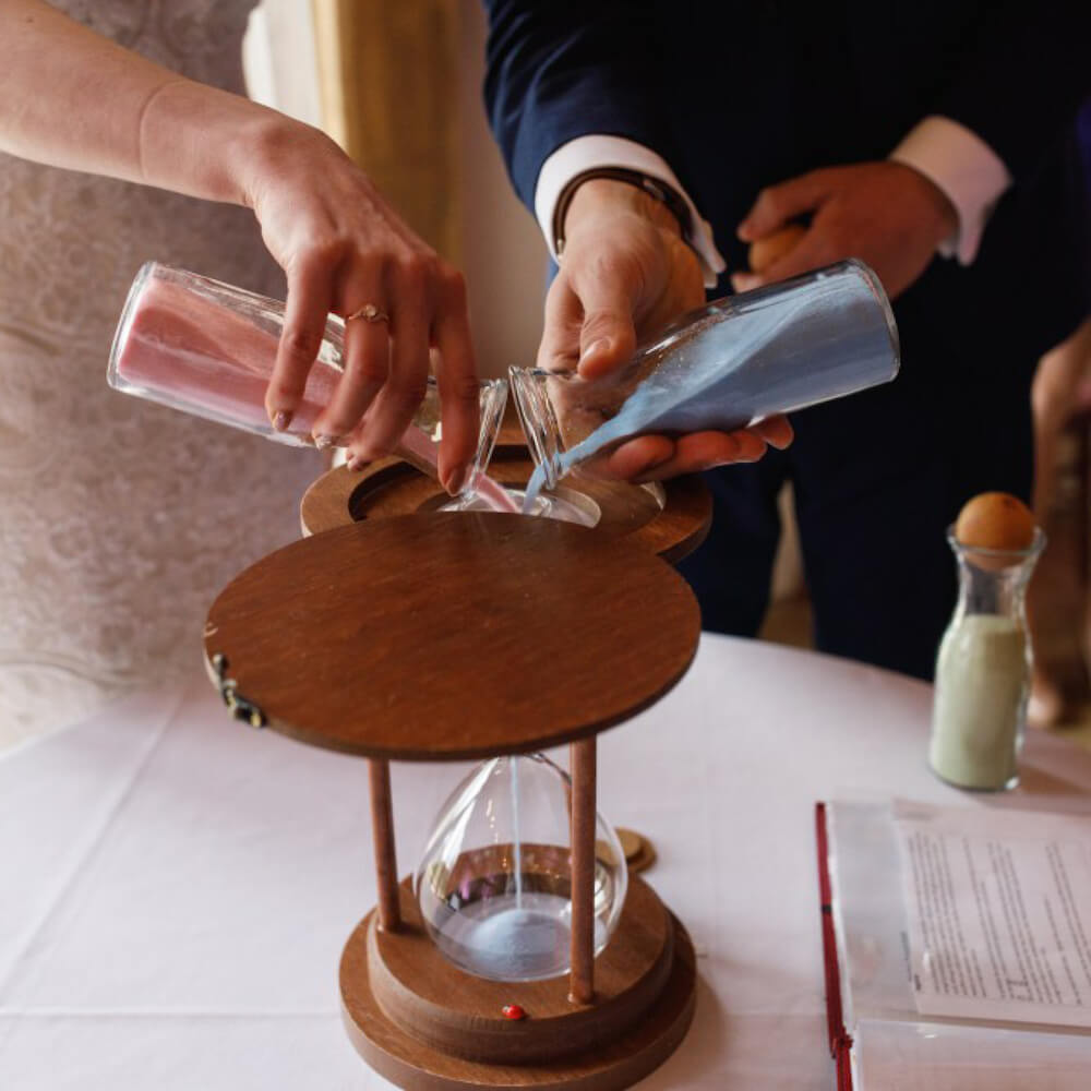 Pouring sand into an hourglass wedding ceremony