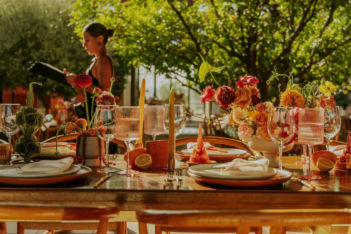 wedding table dressed in hues of amber and reds with a wedding planner walking past